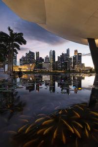 Illuminated city by river against sky