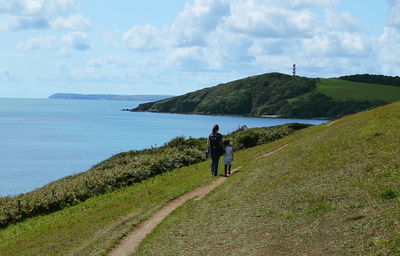 Rear view of man walking on shore against sky