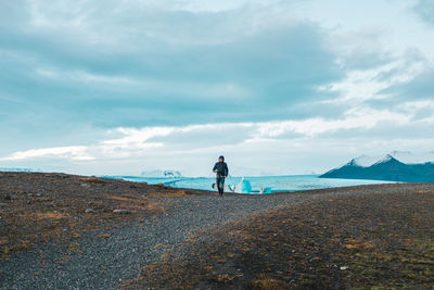 Rear view of man standing on mountain against sky