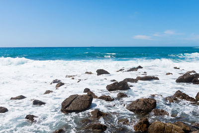 Scenic view of rocks on beach against sky