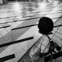 High angle view of boy sitting on tiled floor