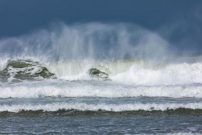 Waves splashing in sea against sky