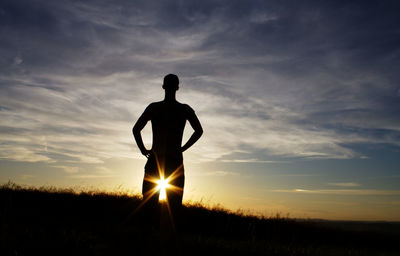 Silhouette man standing on field against sky during sunset