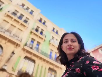 Portrait of smiling woman standing against building
