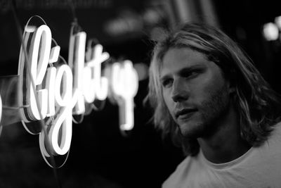 Close-up portrait of young man with illuminated text at night