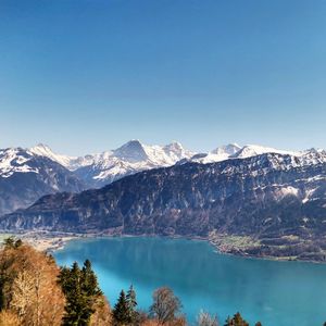 Scenic view of lake and snowcapped mountains against clear blue sky