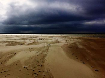 Scenic view of beach against cloudy sky