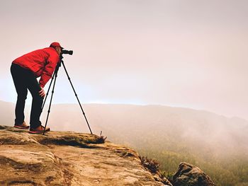 Man photographing on mountain against sky