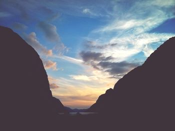 Scenic view of mountains against cloudy sky at sunset