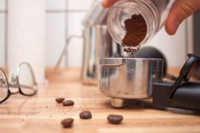 Close-up of hand holding coffee cup on table