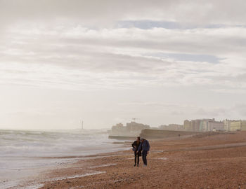 Couple standing on beach against sky