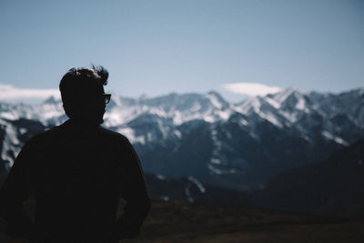 Rear view of man looking at mountain against sky