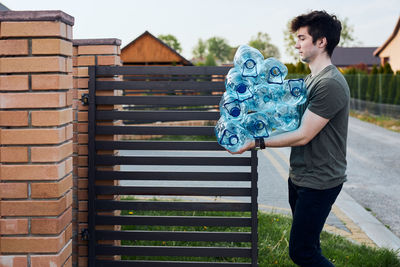 Young man carrying plastic bottles while walking outdoors