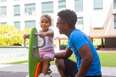 Father playing with his daughter on a pony swing in the park