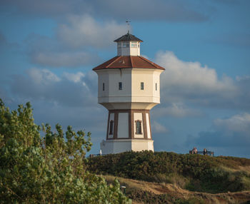 Low angle view of lighthouse by building against sky