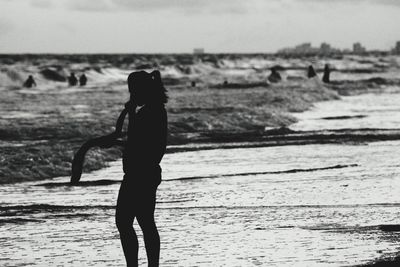 Silhouette woman standing at beach against sky