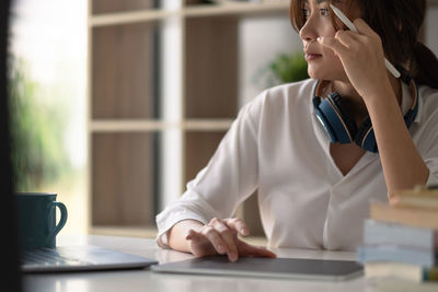 Midsection of woman using mobile phone while sitting on table