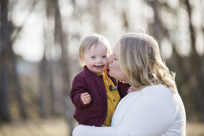 Mother giving baby with down syndrome a kiss on the cheek