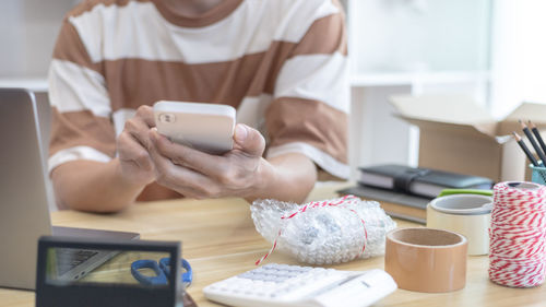 Midsection of woman using mobile phone at table