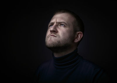 Close-up thoughtful man against black background