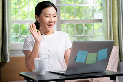 Young woman using mobile phone at table