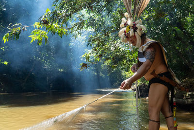 A man wearing traditional borneo clothes is waving a fishing net