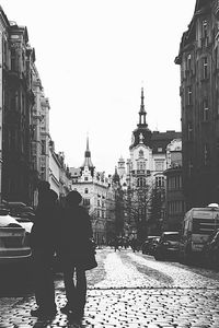 Rear view of people walking on street amidst buildings in city