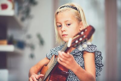 Close-up of girl playing guitar at home