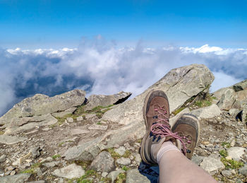 Low section of man standing on mountain against sky