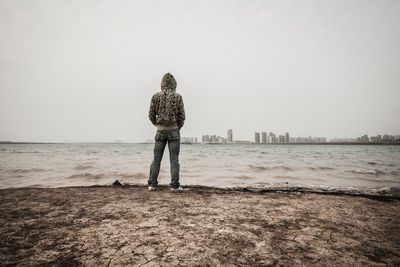 Full length rear view of man standing on shore at beach