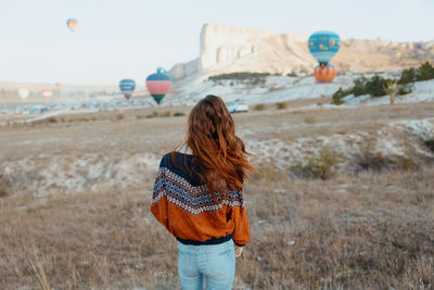 Rear view of woman standing on field against sky