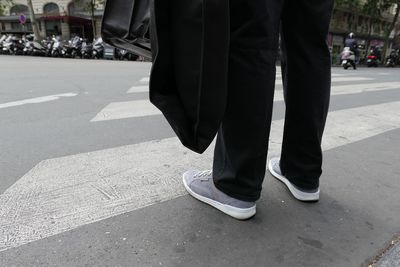 Low section of man standing on zebra crossing in city