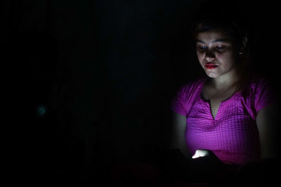 Portrait of woman in illuminated dark room