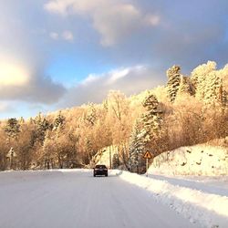 Car on snow covered road against sky