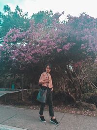 Full length portrait of woman standing on pink tree