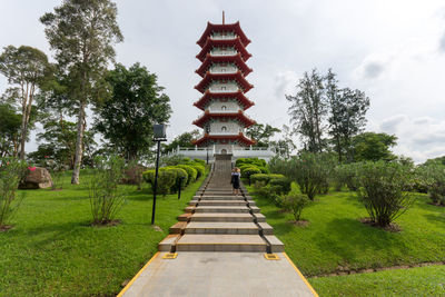 Walkway amidst trees and building against sky