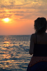 Rear view of woman looking at sea during sunset