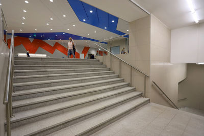 People walking on staircase in illuminated building