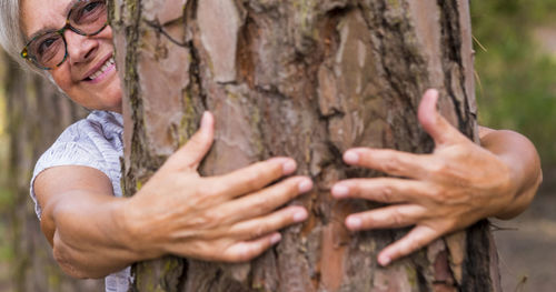 Close-up of hands on tree trunk