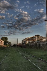 Railroad tracks by buildings against sky during sunset