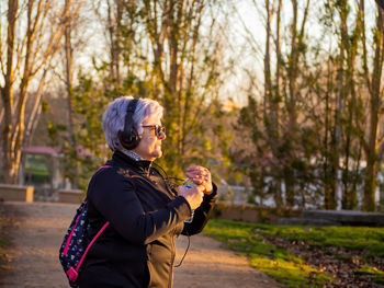Senior woman listening music in park during sunset