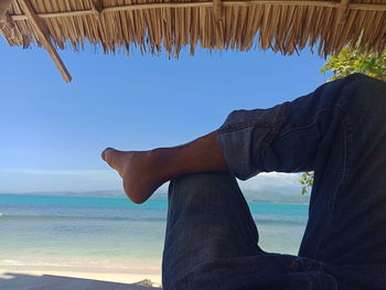 Low section of person on beach against sky