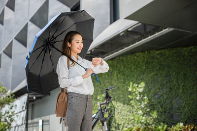 Portrait of young woman standing against building