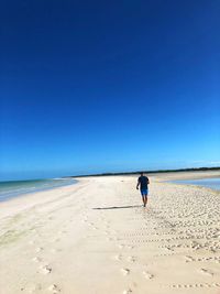 Full length of man on beach against clear blue sky