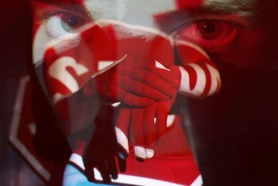 Close-up of man in dark with red light and stop text on face