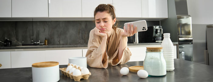 Portrait of young woman standing in kitchen