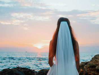 Rear view of bride looking at sea against sky