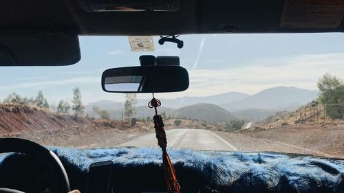 Landscape against cloudy sky seen through car windshield