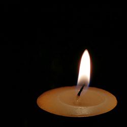 Close-up of lit candle against black background