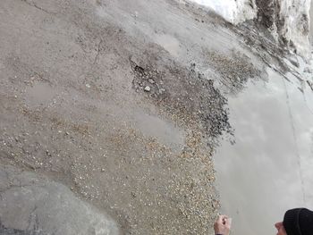 Low section of man standing by water against sky